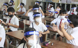 Des enfants à l'école primaire portent des masques et des protections à Osaka au Japon.