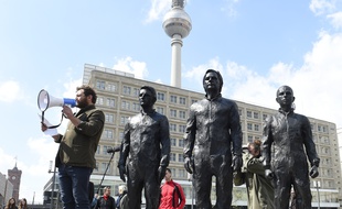 Le sculpteur italien Davide Dormino (G) s'exprime lors de l'inauguration de son monument en bronze représentant Edward Snowden, Julian Assange et Chelsea Manning , le 1er mai 2015 à Berlin.