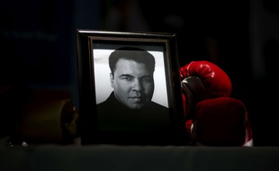 A portrait of Muhammad Ali is displayed next to a pair of boxing gloves at the I Am Ali Festival at the Kentucky Center for the Performing Arts Wednesday, June 8, 2016, in Louisville, Ky. Ali's memorial service Friday looms as one of the most historic events in Louisville's history. (AP Photo/David Goldman)/KYDG118/16160607520523/1606081901