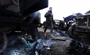 Un combattant Peshmerga au milieu carcasses de voitures après un attentat du groupe Etat islamique à Kesarej en Irak, le 18 décembre 2014