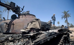 Un rebelle à côté de la carcasse d'un tank de l'armée loyale à Mouammar Kadhafi à Misrata, le 19 avril 2011.