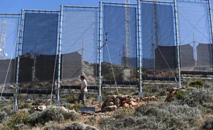 Un homme inspecte le 7 juin 2015 les immenses filets qui servent à capter le brouillard, près de la ville de Sidi Ifni, dans le sud-ouest marocain