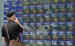 Un homme regarde un tableau d'indices boursiers, le 9 septembre 2015 à Tokyo