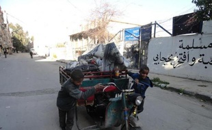 Des garçonnets poussent un véhicule dans une rue du camp de réfugiés palestiniens de Yarmouk, dans le sud de Damas, le 4 avril 2015