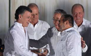 Le président colombien Juan Manuel Santos (à g.) et le chef des Farc Timochenko (à dr.) après la signature de l'accord, en présence du président cubain Raul Castro, à Carthagène, le 26 septembre 2016