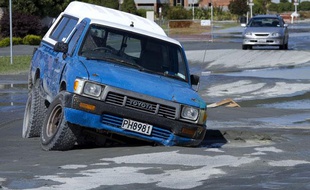Une voiture enfoncée dans la route, après le séisme qui a frappé la banlieue de Christchurch, le 23 décembre 2011.