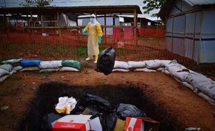 Un travailleur de Médecins sans frontières jette des affaires qui seront incinérées à Kailahun en Sierra Leone le 14 août 2014