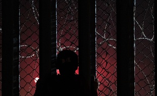 Une silhouette regarde de l'autre côté de la frontière, depuis le Mexique.