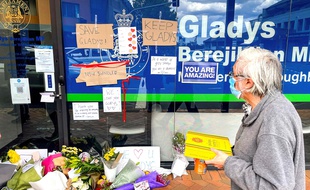 Un homme regarde des fleurs et des pancartes placées par des membres du public devant le bureau local de l'ancienne Première ministre de l'État de Nouvelle-Galles du Sud, Gladys Berejiklian, un jour après sa démission, à Sydney le 2 octobre 2021. (Photo by DAVID GRAY / AFP)