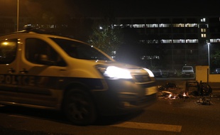 Une voiture de police passe près d'une poubelle incendiée à Villeneuve-la-Garenne, le 20 avril 2020.