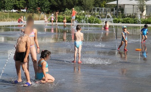 Des enfants s'amusent avec les jets d'eau sur le miroir d'eau, le 1er juillet 2015