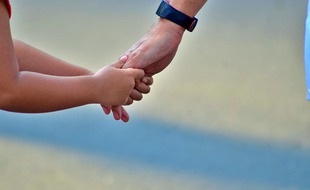 Un parent qui tient la main de son enfant. Illustration.