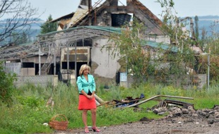 Tout près de Slaviansk, ex-bastion des insurgés pro-russes, dans le village de Semyonovka en Ukraine, une femme attend une voiture devant une maison détruite par les combats, le 9 juillet 2014