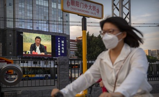 Une femme passe devant un écran diffusant un discours du président chinois Xi Jinping, le 30 juin 2020 à Pékin.