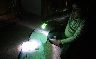 Pénurie: Un petit garçon utilise une lampe électrique pour faire ses devoirs durant une coupure de courant à Bagdad le 19 mars 2014