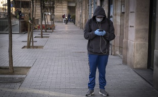 Un utilisateur masqué de smartphone à Barcelone, au temps de Covid-19.