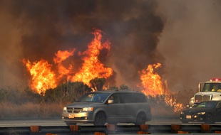 Les automobilistes conduisent cernés par des incendies sur la route US 101 menant à la plage de Faria, au nord de Ventura, en Californie, le 7 décembre 2017.