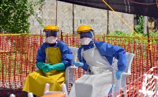 Health workers sit at NGO's Medecins Sans Frontieres (MSF, Doctors Without Borders) Ebola treatment center inside the Samuel K. Doe stadium in Monrovia on October 15, 2014. Dozens of Ebola survivors, now immune to the deadly disease, will meet in Sierra Leone this week to see how they can help tackle the epidemic, the UN said on October 14. AFP PHOTO / ZOOM DOSSO