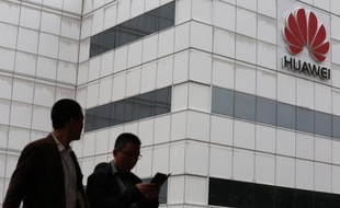 People walk by a building on the Huawei campus L'équipementier chinois en télécommunications Huawei a annoncé lundi une hausse de 32% de son bénéfice net et espère "résoudre les défis et les problèmes" qu'il rencontre aux Etats-Unis qui lui reprochent ses liens avec les autorités chinoises.