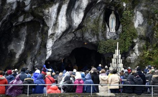 Des pélerins sous la statue de la Vierge Marie, dans la grotte de Massabielle le 11 février 2016 à Lourdes
