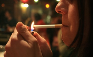 Illustration : une jeune fille allume une cigarette.
