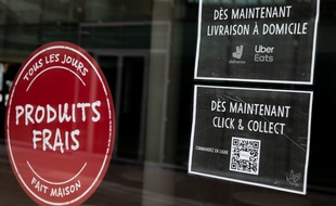 Affichage d'un Click & collect et d'une livraison à domicile sur la façade d'un restaurant de La Défense, à Paris.