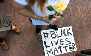 Une femme se tient au dessus d'une pancarte « Black Lives Matter »