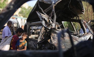 De jeunes Irakiens inspectent une voiture piégée à la bombe à Bagdad le 18 juin 2014