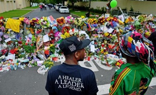 Un petit autel a été improvisé sur la pelouse, autour de deux palmiers nains. Quelques bougies y brûlent encore. Des fleurs s'amoncellent autour, un tee-shirt à l'effigie de Mandela a été accroché au jacaranda voisin, sur lequel quelqu'un a écrit: "Tata Madiba, toujours dans nos coeurs".