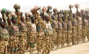 Photo diffusée par le gouvernement nigérian le 26 février 2015 montrant des soldats nigérians engagés dans la lutte contre Boko Haram en train de saluer le président Goodluck Jonathan à son arrivée au village de Mubi, repris aux insurgés