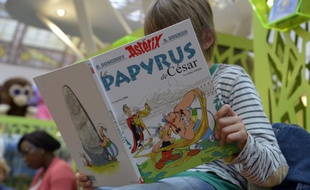 Un enfant lit une BD au salon du livre de Paris.