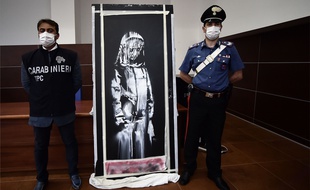 Des carabiniers italiens encadrent l'oeuvre volée attribuée à Banksy.