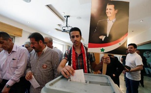 Un Syrien vote le 3 juin 2014 à Damas à l'élection présidentielle, devant une affiche du président sortant Bachar al-Assad, assuré de la victoire