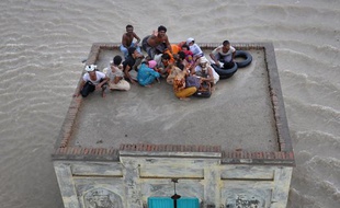 Une famille pakistanaise victime des inondations attend les secours sur le toit d'une mosquée, à Sanawa, dans le Pendjab, le 5 août 2010.