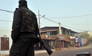 Un membre des forces de sécurité en poste devant le restaurant "La terrasse" (rideaux bleus) à Bamako le 7 mars 2015