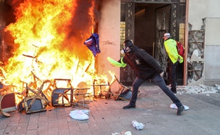 Paris, le 16 mars 2019. Un manifestant jette un drapeau européen dans un brasier allumé devant un magasin situé sur les Champs-Elysées.