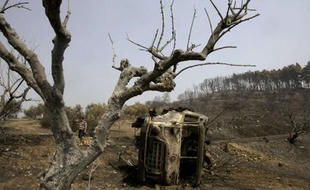 Un véhicule des pompiers carbonisés vers le village de Artemida en Grèce