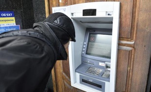 Un homme devant un distributeur de billet (photo illustration)