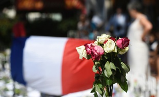 Des roses fanées posées près d'un drapeau national français, le 16 juillet 2016 sur la Promenade des Anglais à Nice