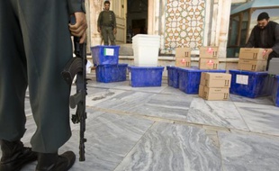 Un policier afghan tient la garde devant du matériel de vote à Herat, Afghanistan.