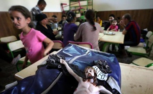 Une statue de Jésus Christ est posée sur le sac d'un Irakien chrétien qui s'apprête à quitter sa ville de Qaraqosh, où sévissent les jihadistes, le 7 août 2014