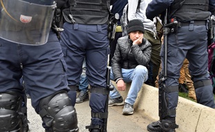 Des migrants de la «Jungle» derrière un cordon de policiers.