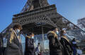 Des personnes avec un masque devant la Tour Eiffel, à Paris le 21 décembre 2021.