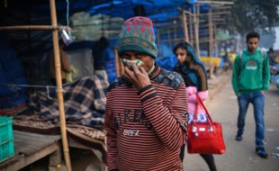 Un passant tente de se protéger de la pollution le 18 décembre 2015 dans le quartier d'Anand Vihar à New Delhi