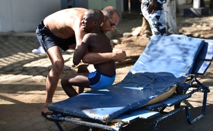 Un homme aide un enfant blessé lors d'une attaque par des gens d'armés de la station balnéaire de Grand-Bassam, en Côte d'Ivoire.