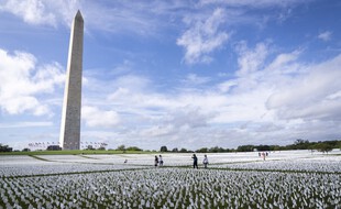Des passants au milieu des drapeaux de l'installation «In America: Remember», qui commémore les Américains décédés du coronavirus sur le National Mall, le 21 septembre 2021 à Washington.
