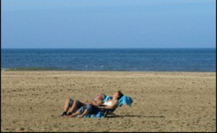 Un couple prend un bain de soleil sur la plage de Deauville