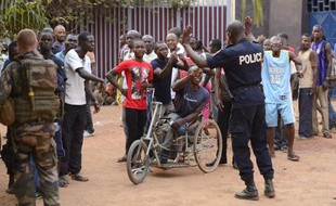 Un policier centrafricain et un soldat français contiennent une foule alors que d'autres soldats français arrêtent des hommes porteurs d'explosifs, le 17 janvier 2014 à Bangui