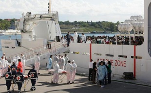 Des migrants se préparent à sortir du beateau de la marine italienne, dans le port de Brindisi, venu les secourir au large de la Sicile, le 15 septembre 2014