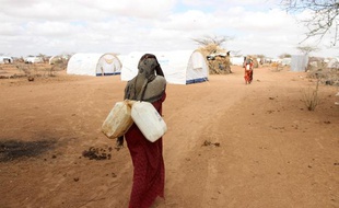 Une réfugiée somalienne porte des jerricans d'eau dans un camp à la frontière avec le Kenya, en avril 2011.
